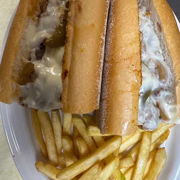 Philly cheesesteak sandwich served with crispy French fries